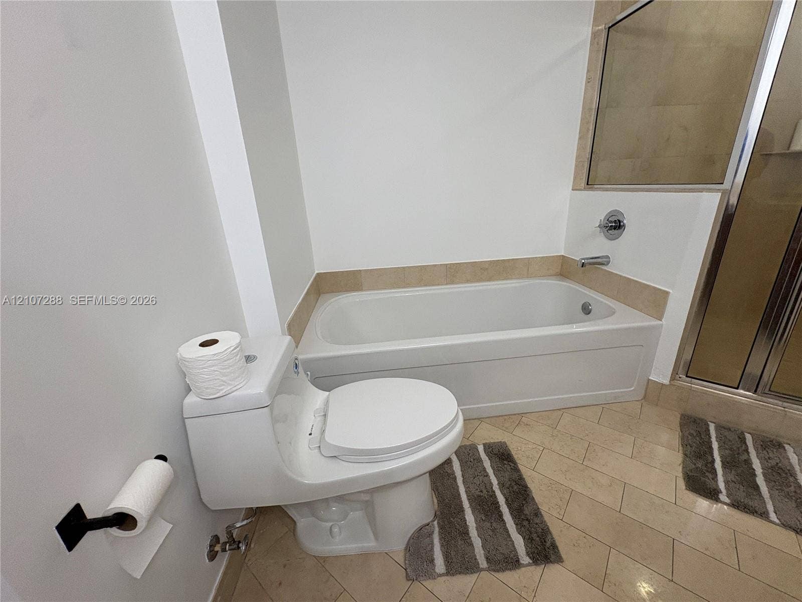 Built-in soaking tub with a tiled surround, separate shower enclosure with metal framing, and tile flooring