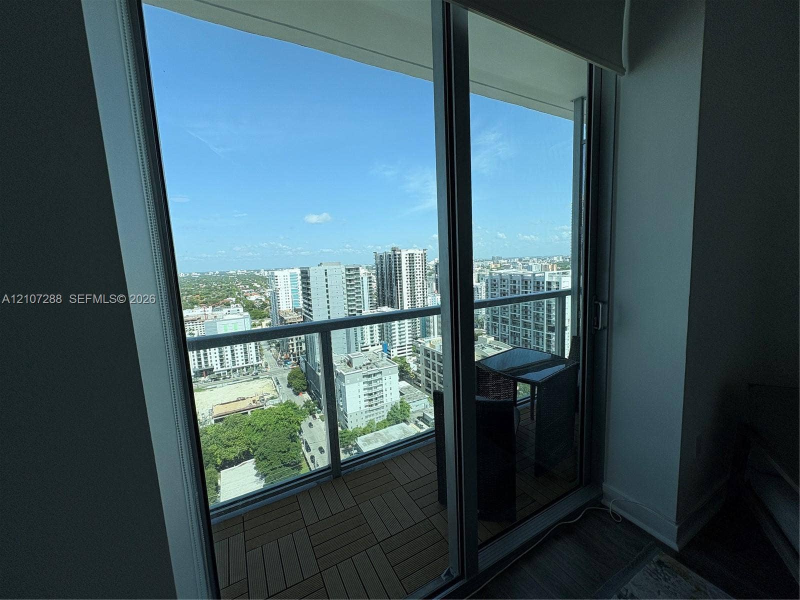 Balcony featuring interlocking composite wood-finish decking and floor-to-ceiling sliding glass doors with a metal frame