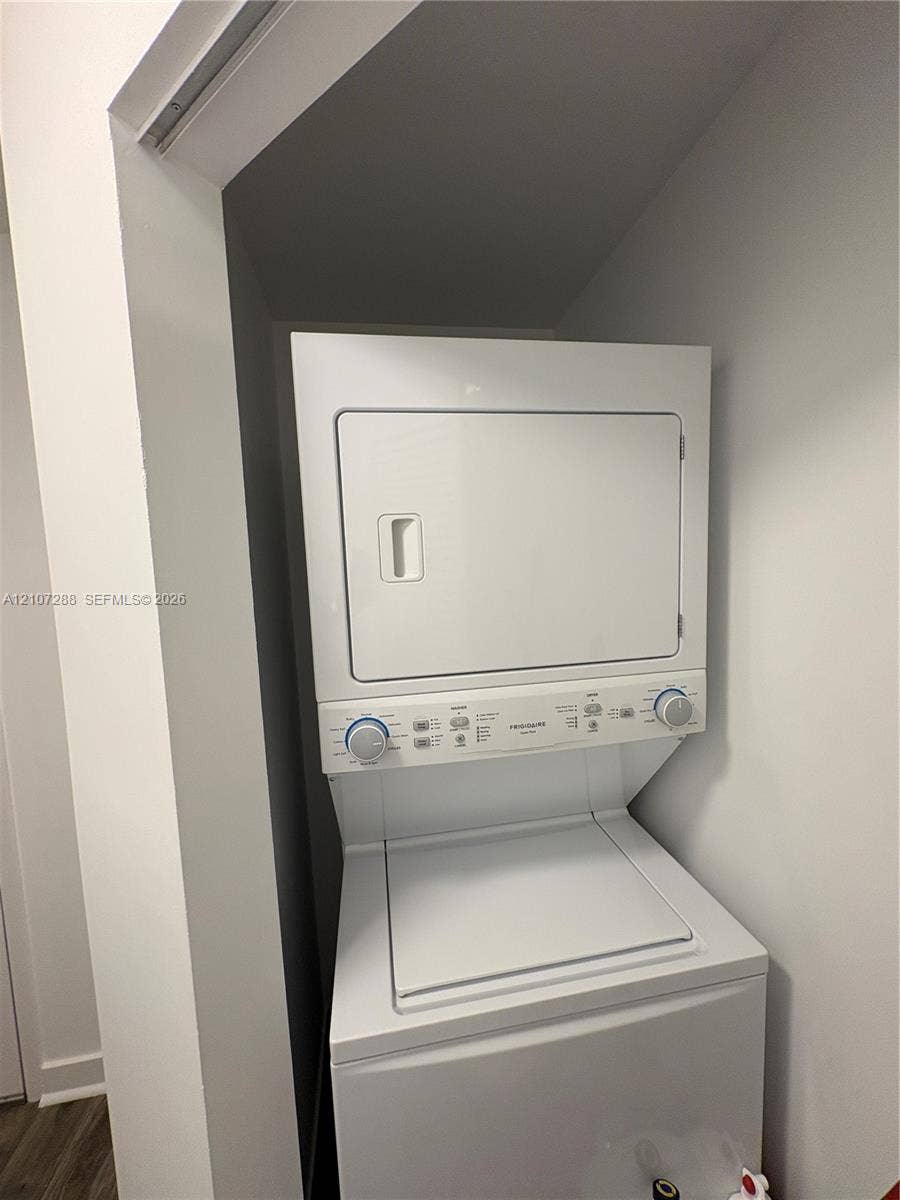 Stackable white laundry unit featuring a top-load washer and front-load dryer in a dedicated recessed closet