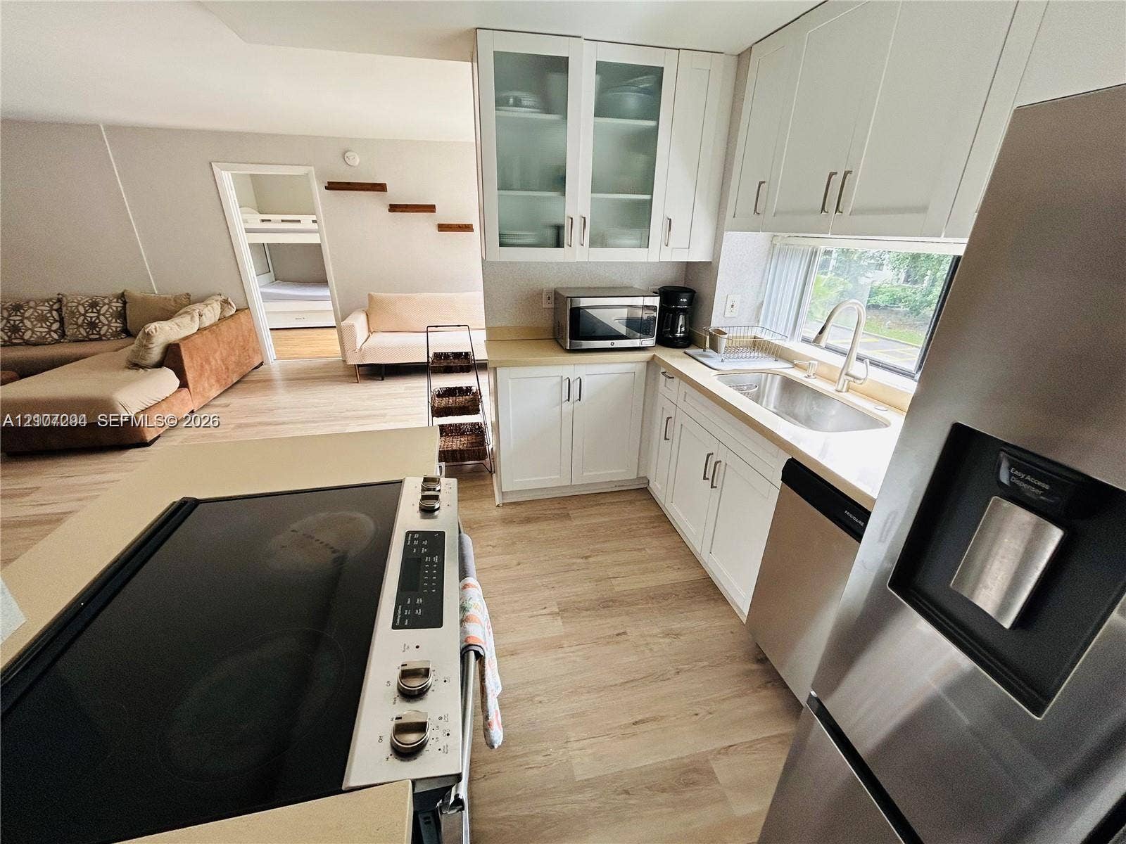 17021 N Bay Road, #219, Sunny Isles Beach, Sunny Isles Beach, FL 33160 Kitchen featuring white cabinetry, glass-front upper cabinets, stainless steel appliances, and wood-finish flooring