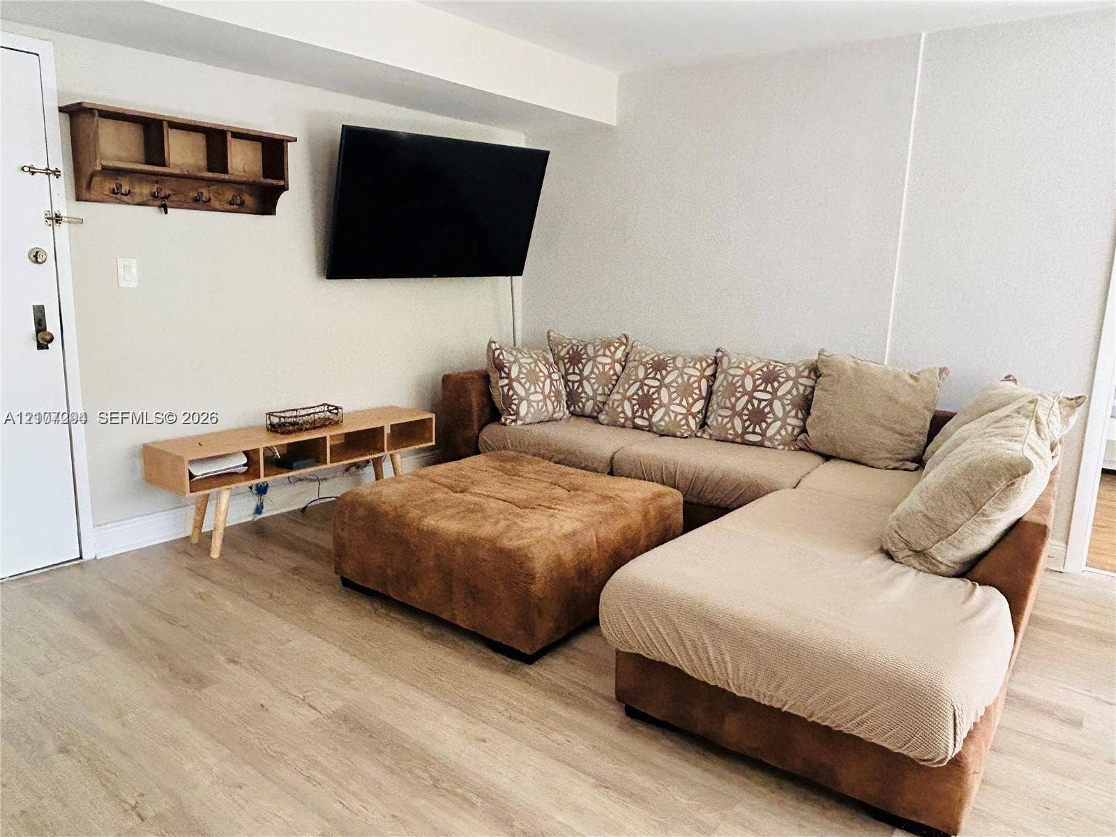 17021 N Bay Road, #219, Sunny Isles Beach, Sunny Isles Beach, FL 33160 Interior space featuring neutral wall tones, wood-finish flooring, and a wall-mounted wooden storage shelf with integrated hooks