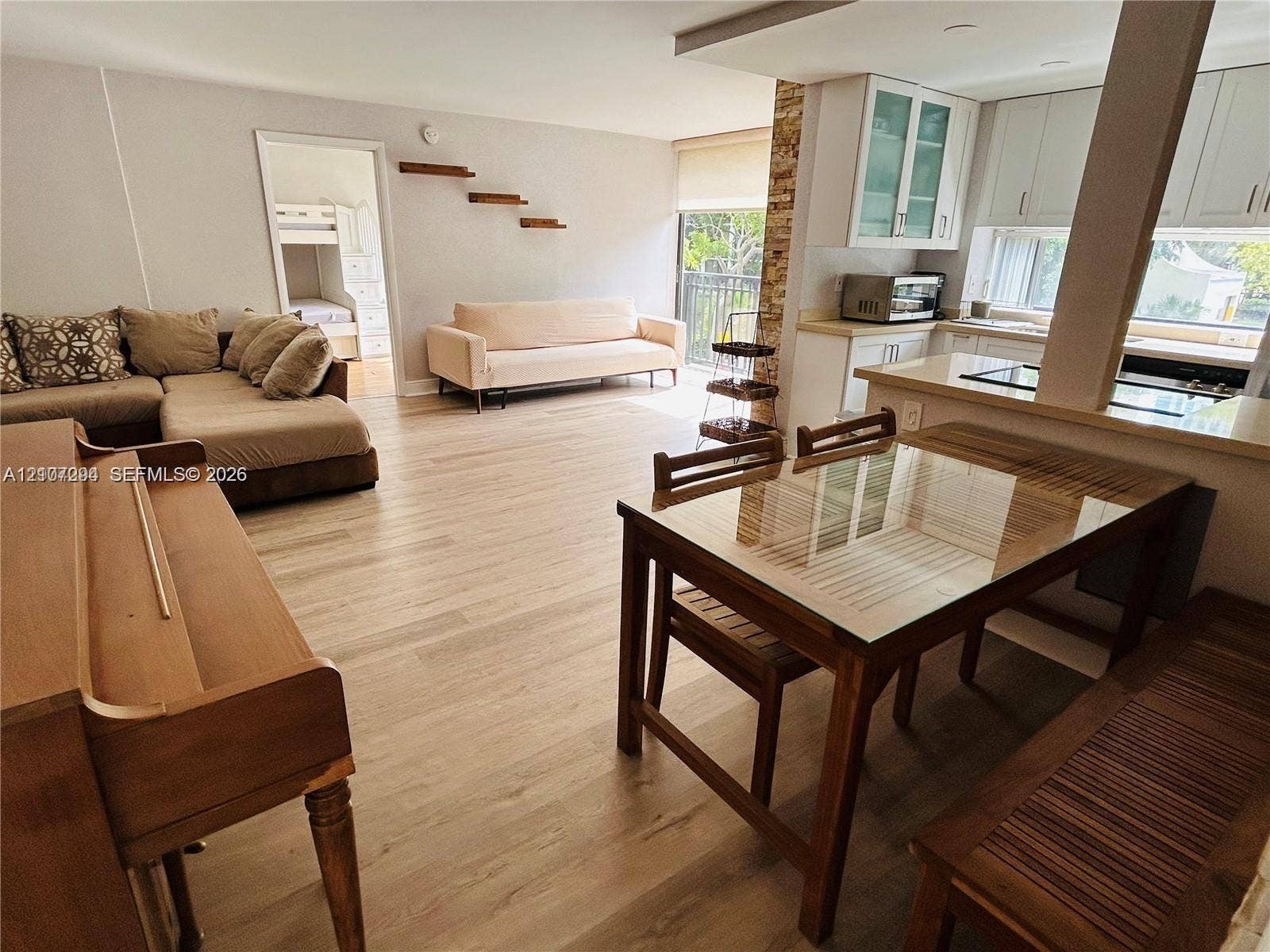 17021 N Bay Road, #219, Sunny Isles Beach, Sunny Isles Beach, FL 33160 Open-concept interior featuring light wood-finish flooring, white cabinetry, quartz-surface countertops, and decorative stone accent wall detailing
