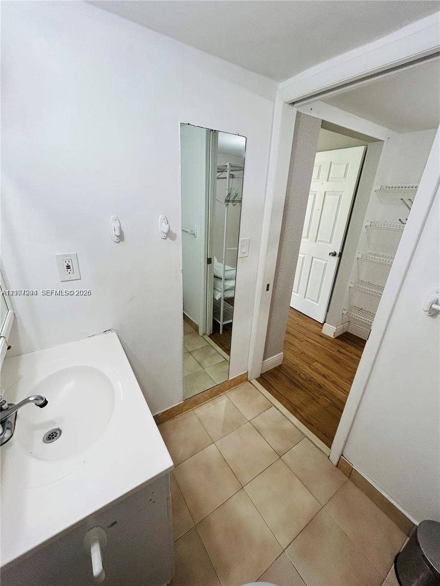 17021 N Bay Road, #219, Sunny Isles Beach, Sunny Isles Beach, FL 33160 Vanity featuring a white integrated sink, ceramic tile flooring, and flush-mounted wall mirror