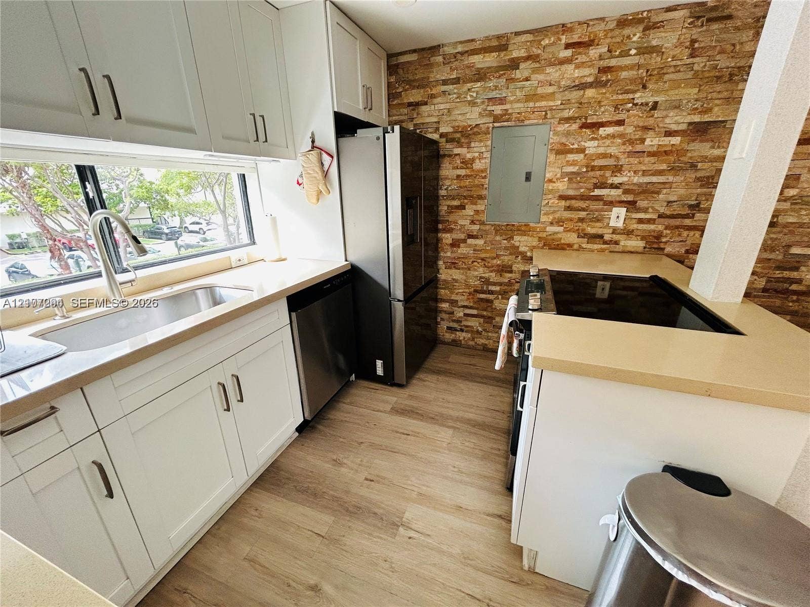 17021 N Bay Road, #219, Sunny Isles Beach, Sunny Isles Beach, FL 33160 Kitchen featuring white shaker cabinetry, stacked stone backsplash, stainless steel appliances, wood-finish flooring, and solid-surface countertops
