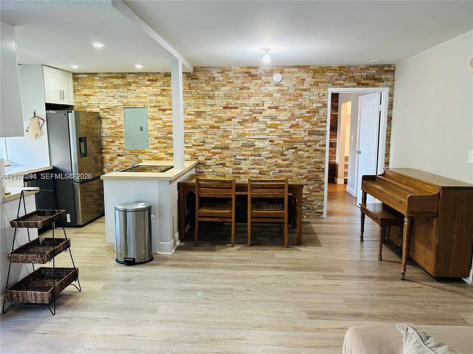 17021 N Bay Road, #219, Sunny Isles Beach, Sunny Isles Beach, FL 33160 Interior space featuring a floor-to-ceiling stone veneer accent wall, wood-finish flooring, and a kitchen peninsula with a stainless steel refrigerator