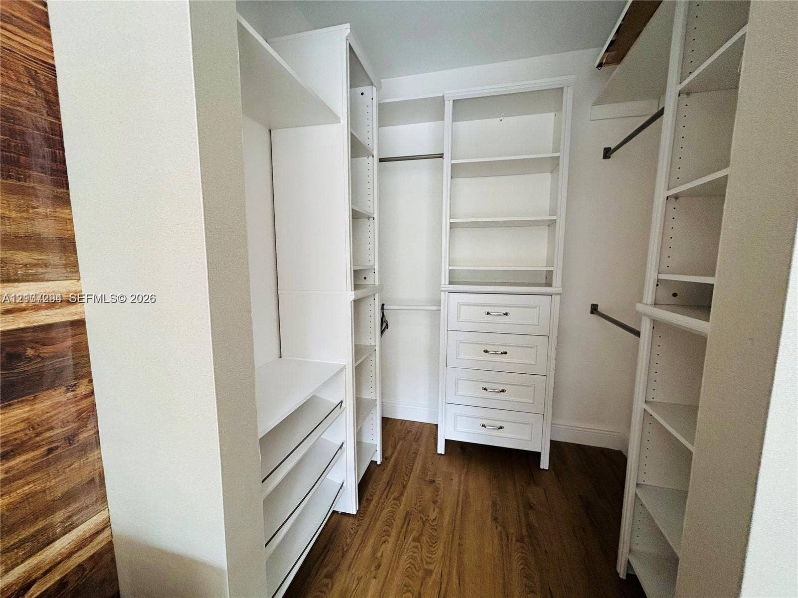 17021 N Bay Road, #219, Sunny Isles Beach, Sunny Isles Beach, FL 33160 Walk-in closet featuring custom white built-in shelving, a four-drawer dresser unit, integrated hanging rods, and wood-finish flooring