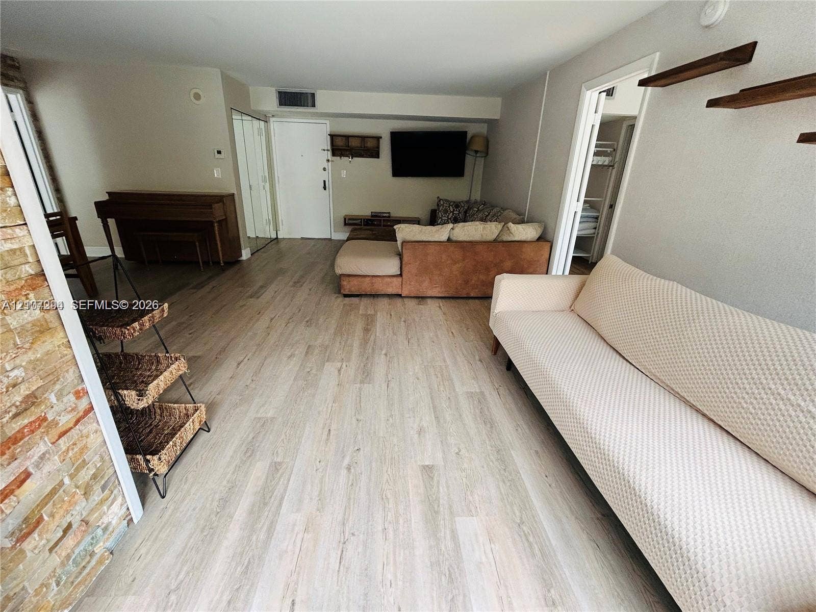 17021 N Bay Road, #219, Sunny Isles Beach, Sunny Isles Beach, FL 33160 Open-concept interior featuring wood-finish flooring, a textured stone accent wall, and dual wall-mounted floating shelves