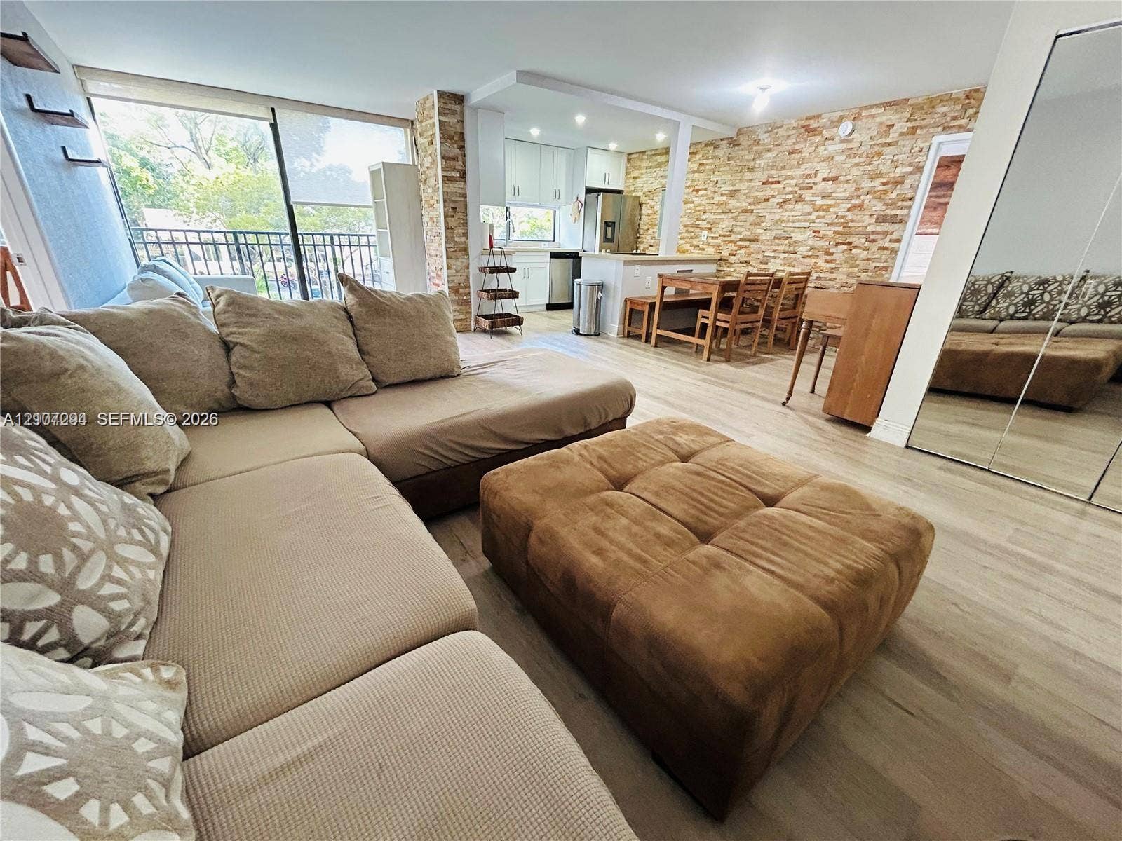 17021 N Bay Road, #219, Sunny Isles Beach, Sunny Isles Beach, FL 33160 Open-concept living space featuring wood-finish flooring, a full-height stone veneer accent wall, recessed lighting, and glass sliding doors providing exterior access