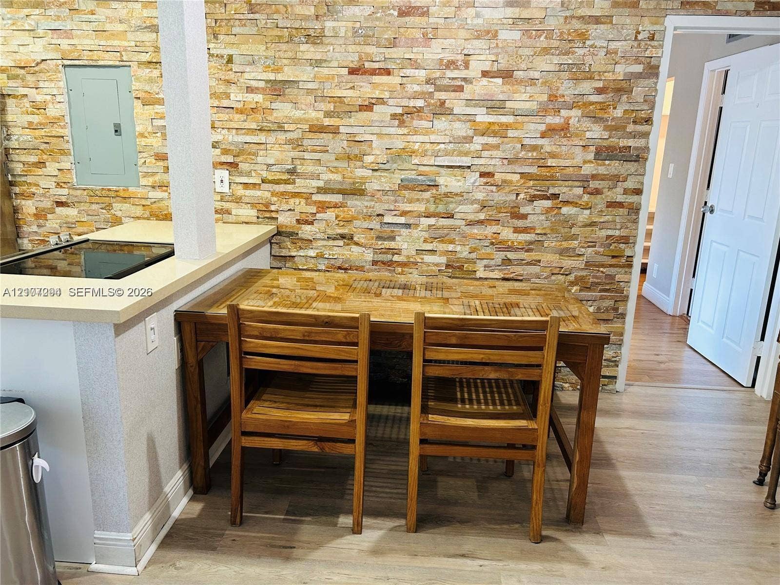 17021 N Bay Road, #219, Sunny Isles Beach, Sunny Isles Beach, FL 33160 Stacked stone accent wall with wood-finish flooring and a kitchen counter featuring a solid surface countertop