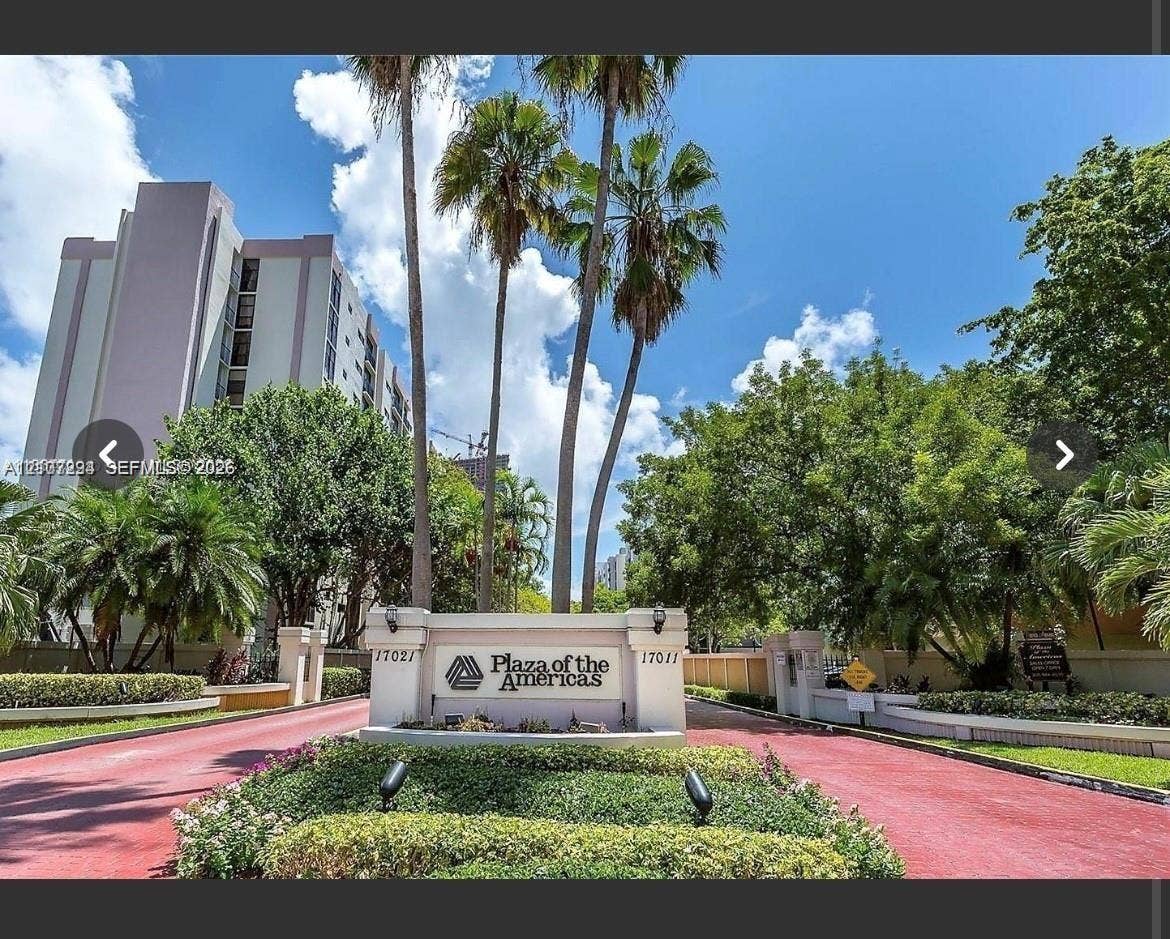17021 N Bay Road, #219, Sunny Isles Beach, Sunny Isles Beach, FL 33160 Gated entrance monument with integrated lighting, paved driveway, mature palm trees, and professional landscaping