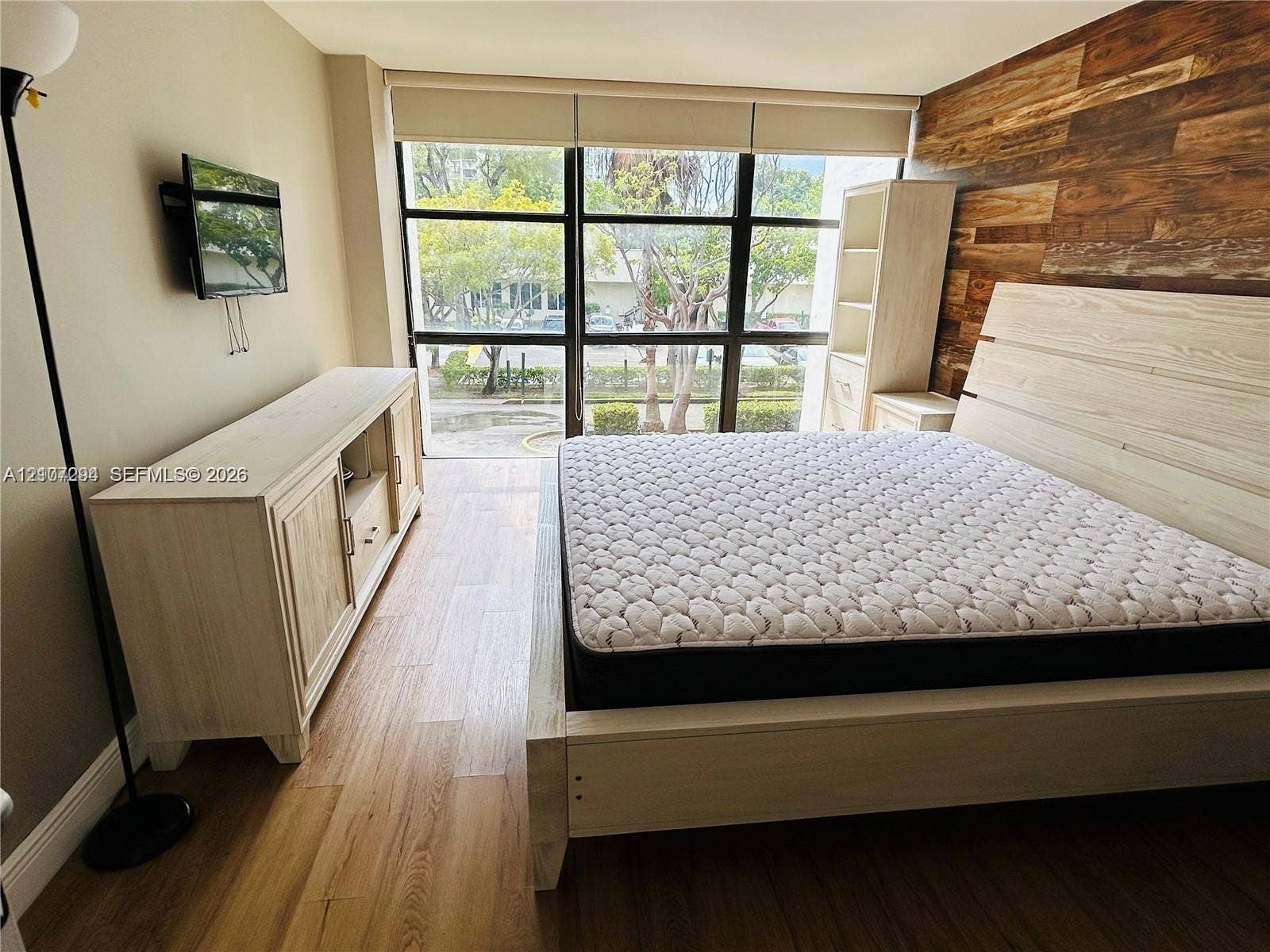 17021 N Bay Road, #219, Sunny Isles Beach, Sunny Isles Beach, FL 33160 Wood-finish flooring, floor-to-ceiling windows with grid frames, and natural wood-plank accent wall