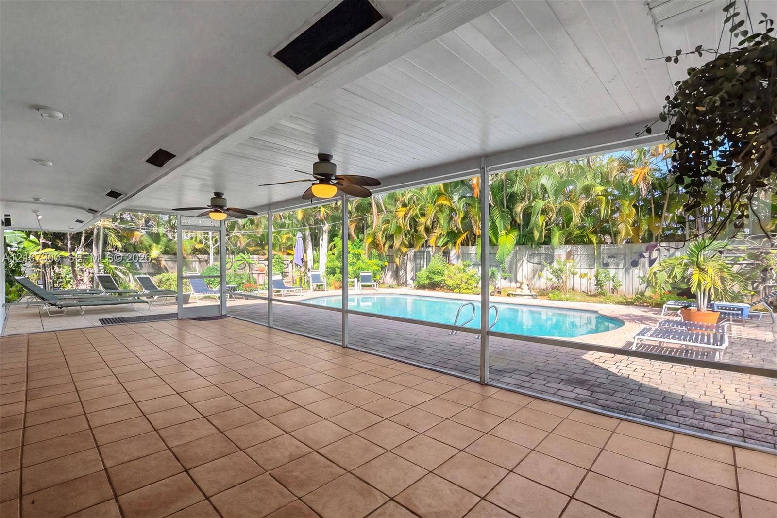 2051 NE 68th Street, Fort Lauderdale, FL 33308 Screened-in lanai featuring tiled flooring, recessed ceiling lighting, and overhead paddle fans, opening to a swimming pool with a paver patio