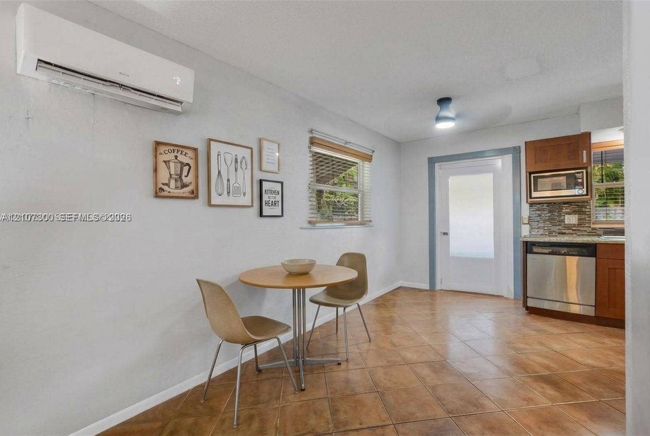 2051 NE 68th Street, Fort Lauderdale, FL 33308 Wall-mounted mini-split HVAC unit, tile flooring, built-in stainless steel dishwasher, built-in microwave, and wood-finish cabinetry