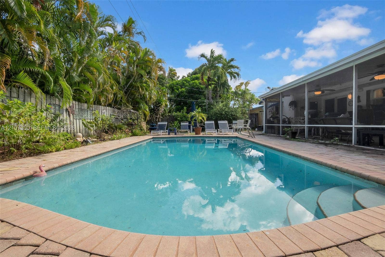 2051 NE 68th Street, Fort Lauderdale, FL 33308 In-ground swimming pool with brick paver coping, screened-in lanai, and lush perimeter landscaping