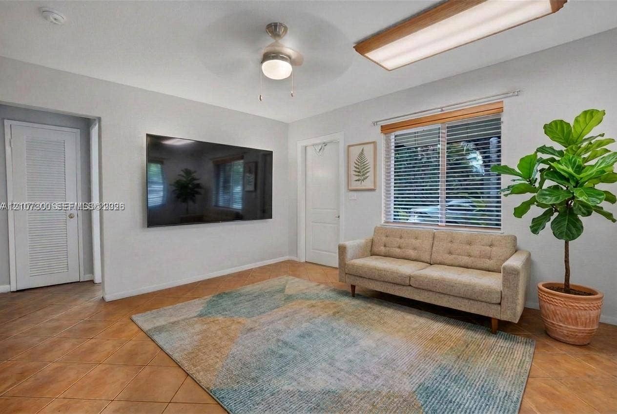 2051 NE 68th Street, Fort Lauderdale, FL 33308 Ceramic tile flooring, neutral wall tones, multi-panel interior doors, window with horizontal blinds, and ceiling fan with integrated lighting