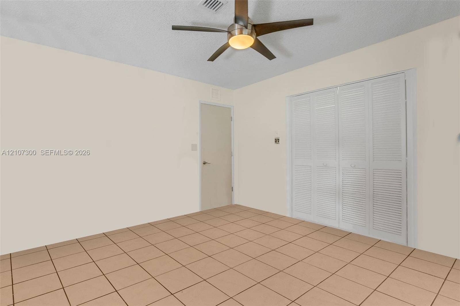 2051 NE 68th Street, Fort Lauderdale, FL 33308 Room featuring ceramic tile flooring, a brushed-metal ceiling fan with integrated lighting, and white louvered-style closet doors