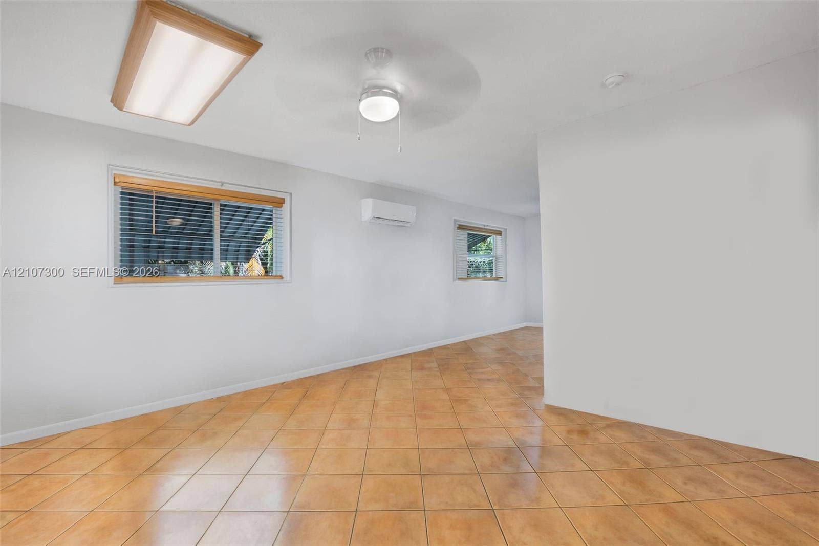 2051 NE 68th Street, Fort Lauderdale, FL 33308 Interior space featuring tile flooring, ceiling-mounted lighting, a ceiling fan, and a wall-mounted ductless air conditioning unit