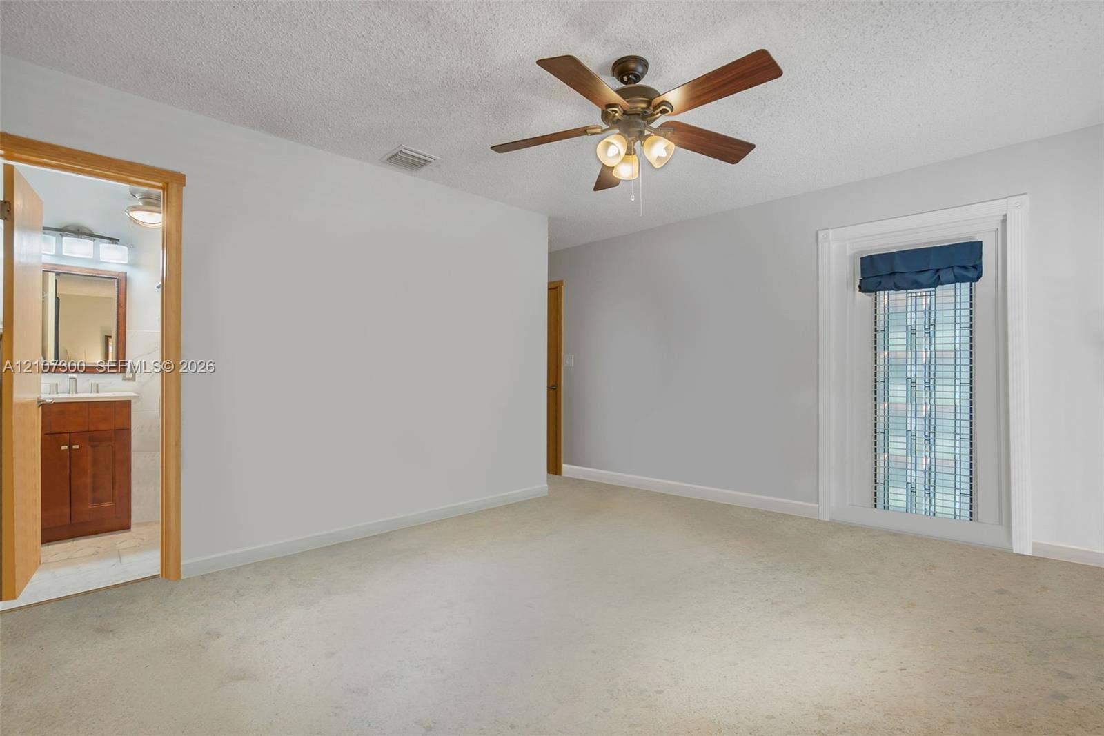 2051 NE 68th Street, Fort Lauderdale, FL 33308 Interior space featuring carpeting, a multi-blade ceiling fan with integrated lighting, and a single-pane window with interior trim