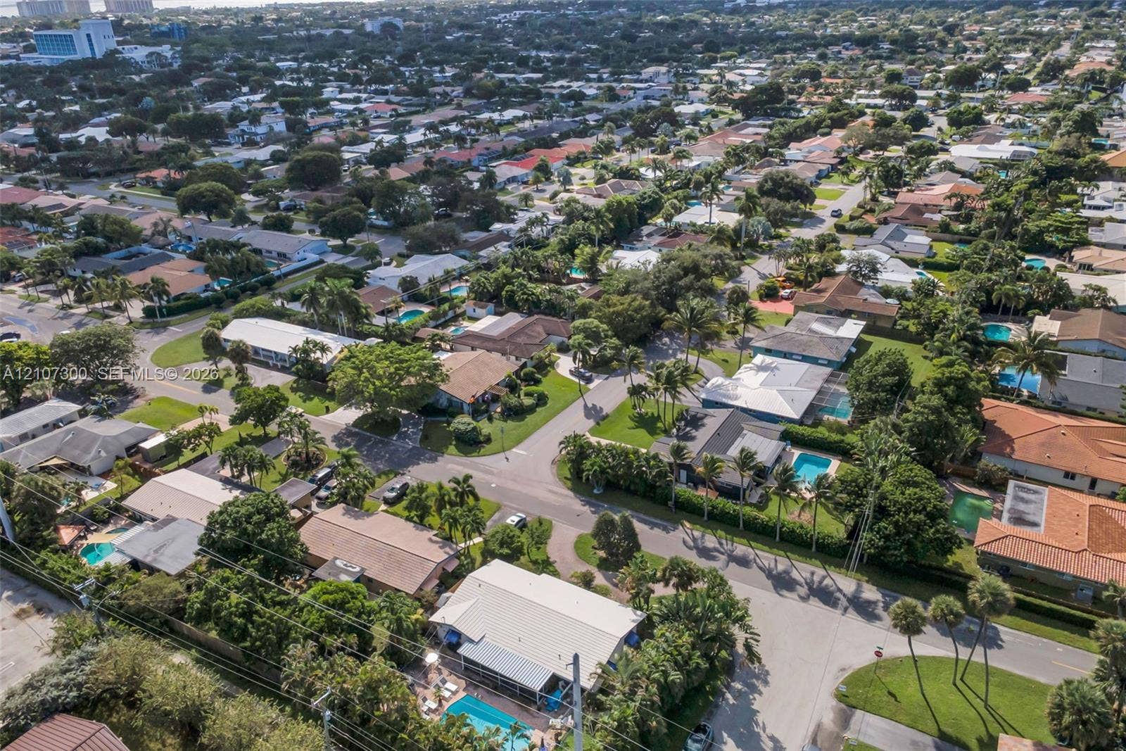 2051 NE 68th Street, Fort Lauderdale, FL 33308 Aerial perspective of a suburban neighborhood featuring residential lots with mature trees, paved streets, and private swimming pools