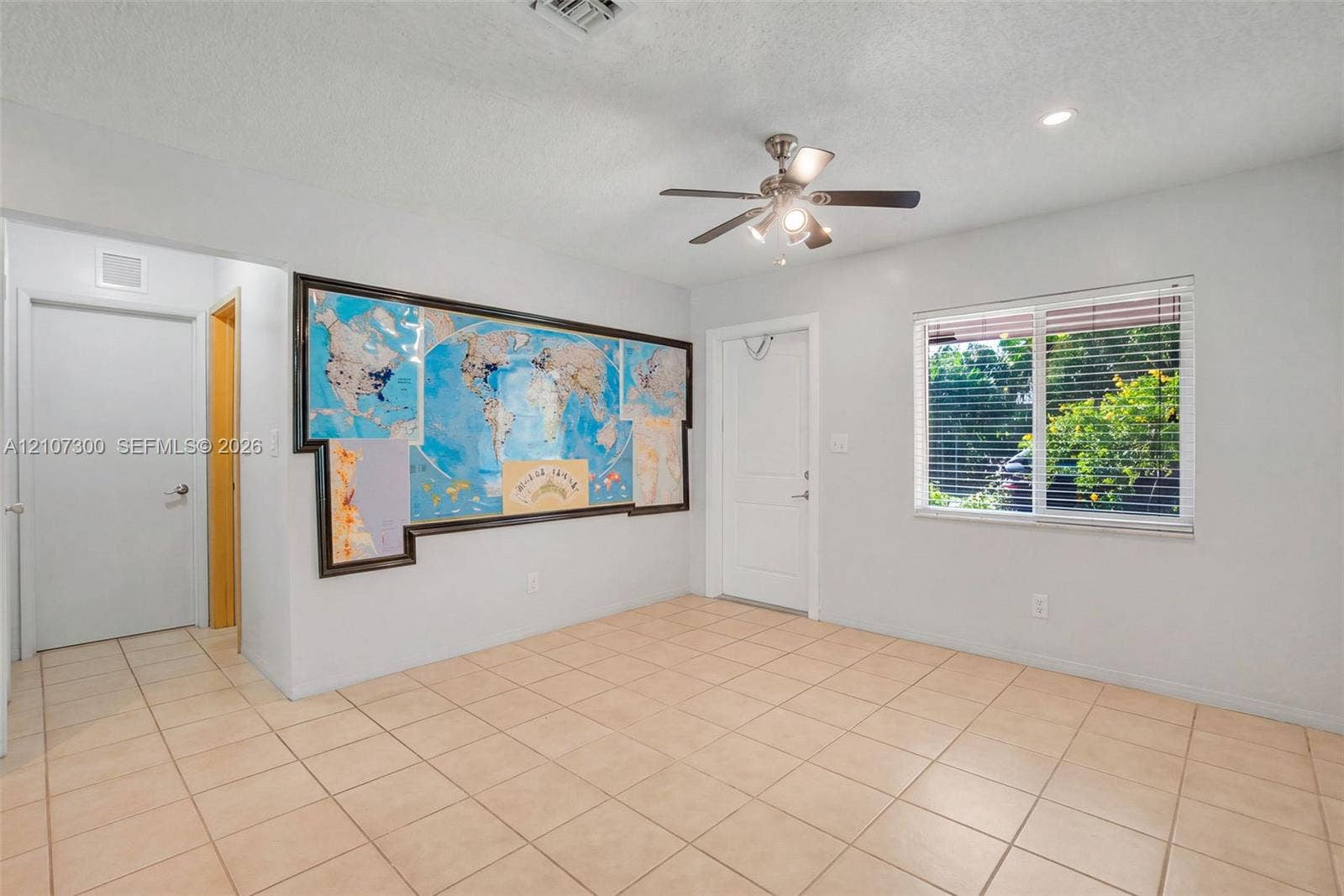2051 NE 68th Street, Fort Lauderdale, FL 33308 Interior space featuring neutral tile flooring, a multi-blade ceiling fan with integrated lighting, and a horizontal sliding window