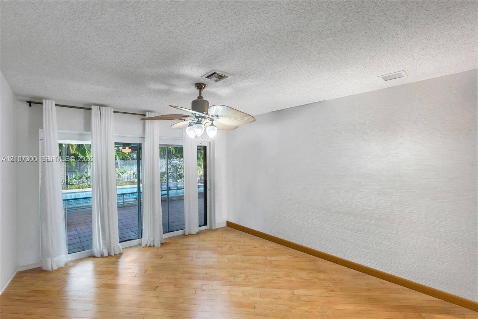 2051 NE 68th Street, Fort Lauderdale, FL 33308 Wood-finish flooring, textured ceilings, ceiling fan with integrated lighting, and glass sliding doors featuring exterior access