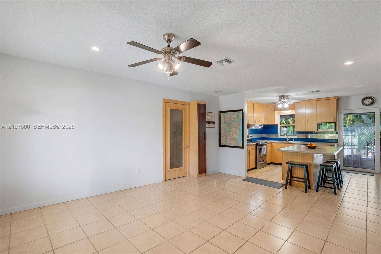 2051 NE 68th Street, Fort Lauderdale, FL 33308 Open-concept interior featuring light-toned cabinetry, a stone-topped kitchen island, recessed lighting, ceiling fans, and neutral floor tiling