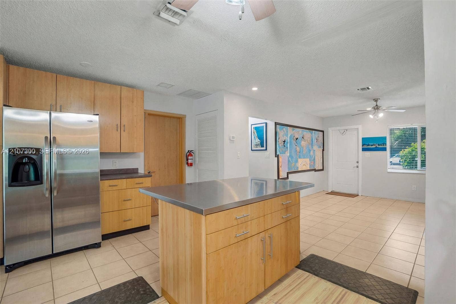 2051 NE 68th Street, Fort Lauderdale, FL 33308 Kitchen featuring wood cabinetry, stainless steel refrigerator, stainless steel island countertop, and tiled flooring