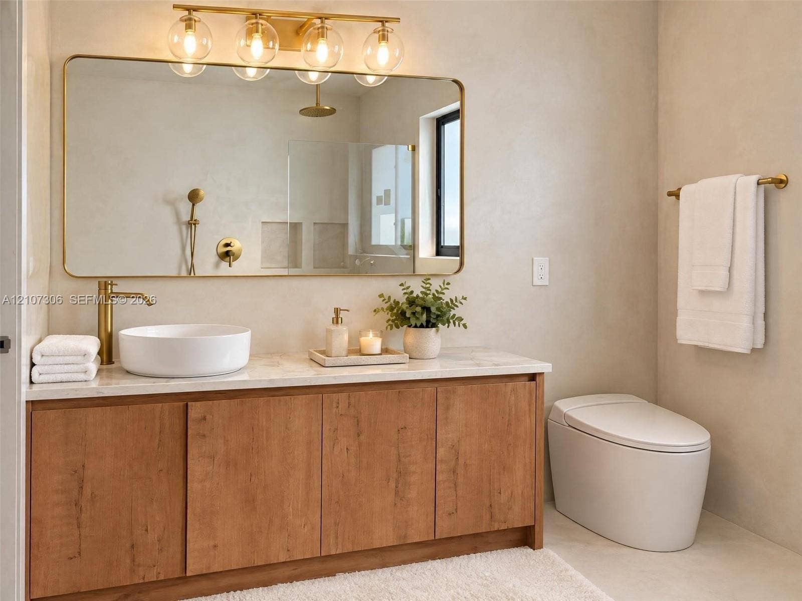4322 Alton Road, Miami Beach, FL 33140 Bathroom vanity featuring a wood-finish cabinet, stone-top surface, vessel sink, and brass fixtures, complemented by a large gold-framed wall mirror with multi-globe light fixture