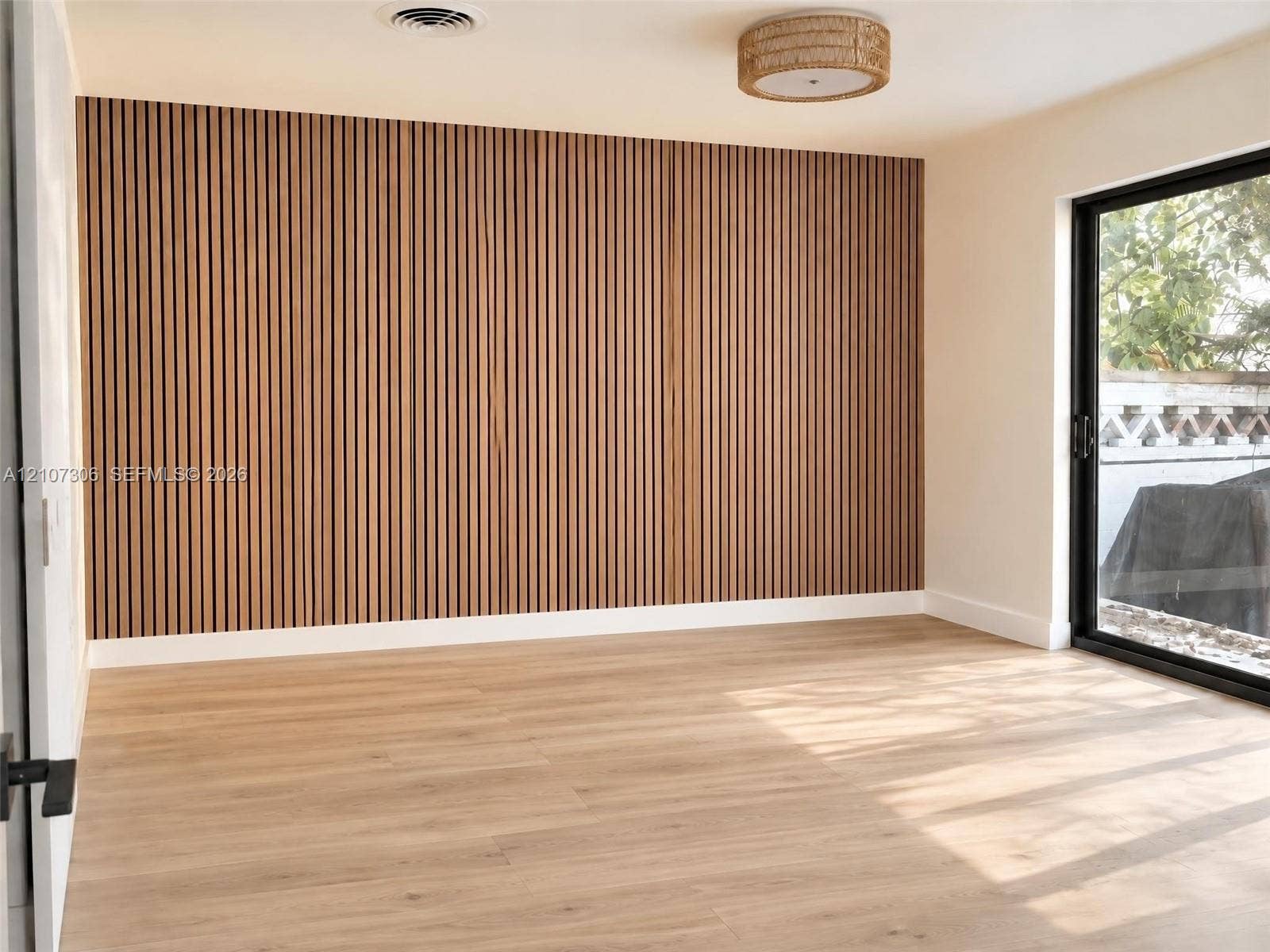 4322 Alton Road, Miami Beach, FL 33140 Vertical wood slat accent wall, light-toned wood-finish flooring, sliding glass door, and integrated circular drum lighting fixture