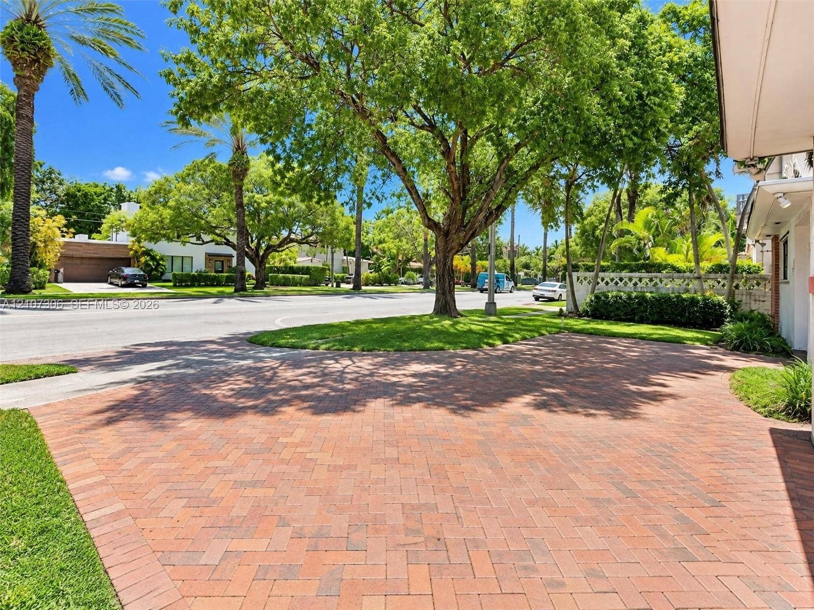 4322 Alton Road, Miami Beach, FL 33140 Brick-paver driveway with a herringbone pattern, mature trees, manicured lawn, and perimeter landscaping