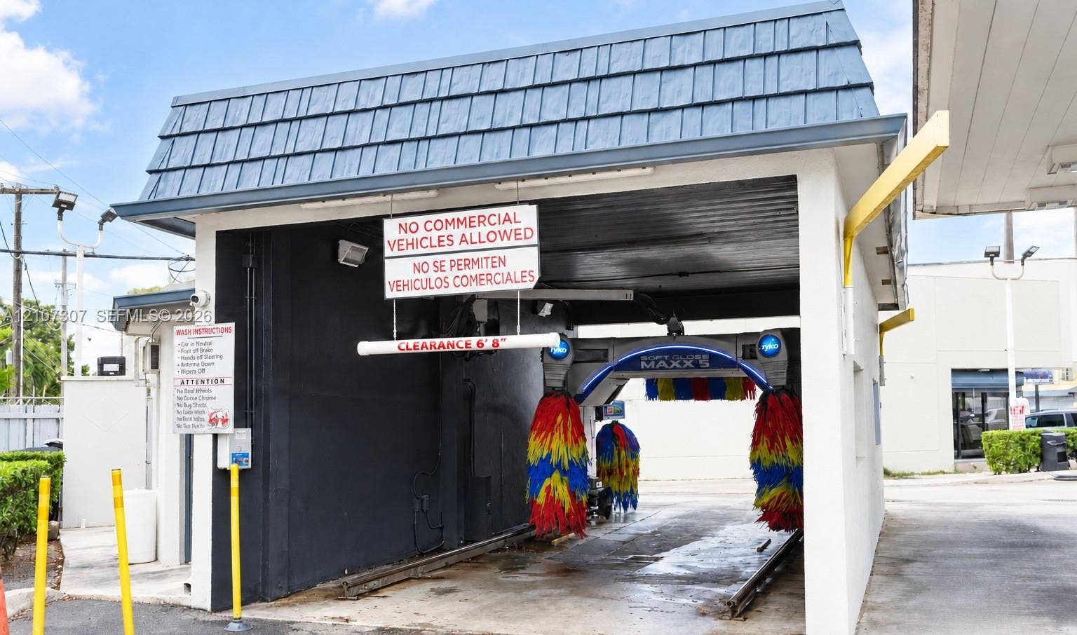 Automated car wash facility featuring a covered bay with built-in cleaning machinery, rail-guided track system, and reinforced concrete structure