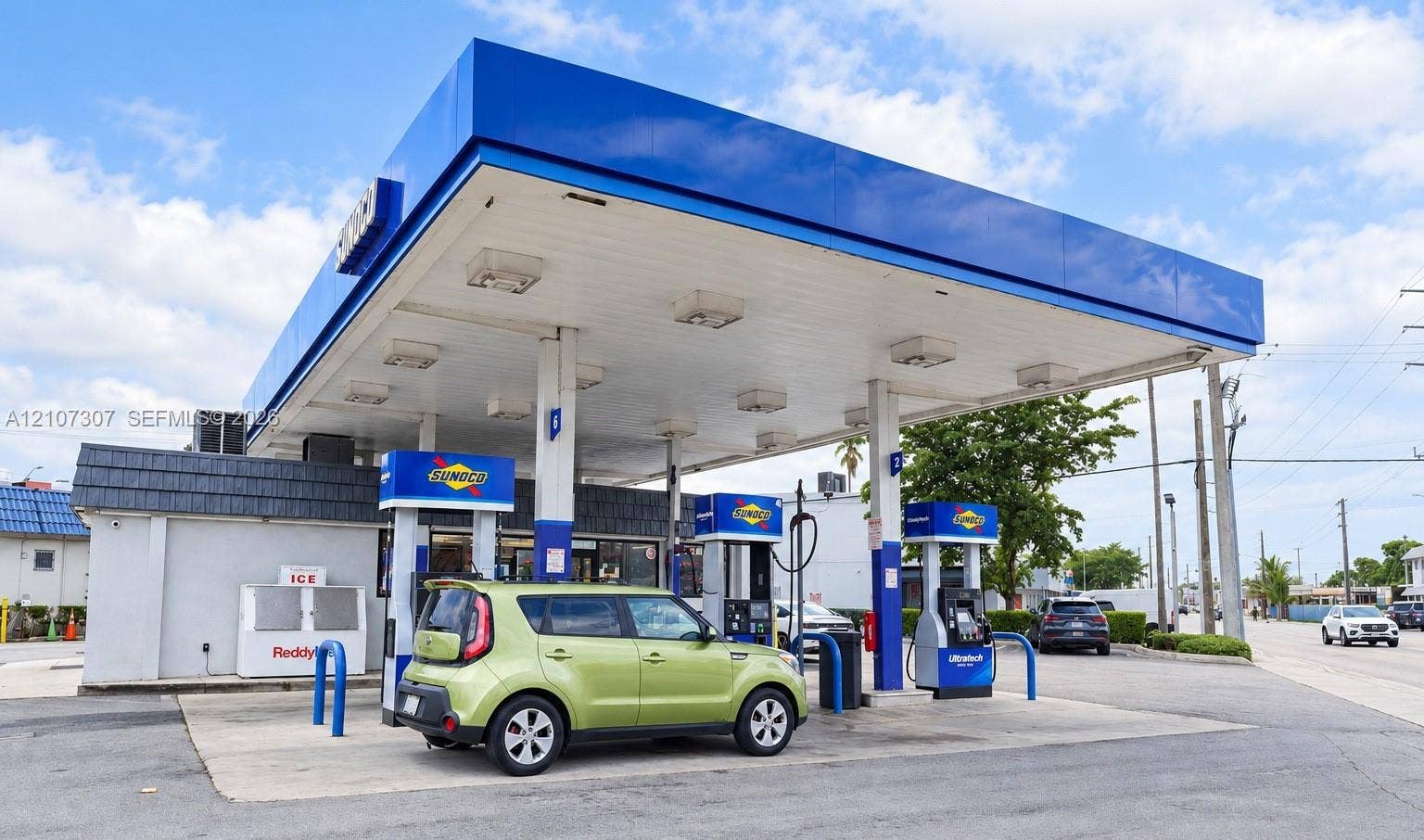 Commercial fueling station featuring a cantilevered canopy, concrete pavement, multiple fuel dispensers, and an integrated retail structure