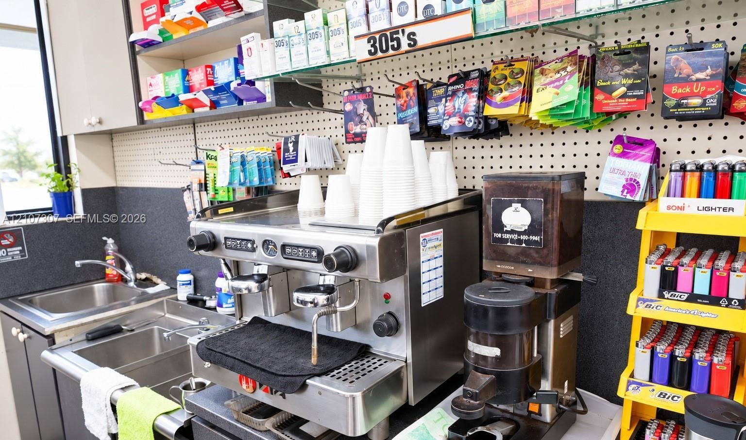 Stainless steel espresso machine, professional-grade coffee grinder, integrated stainless steel sink, and wall-mounted pegboard shelving