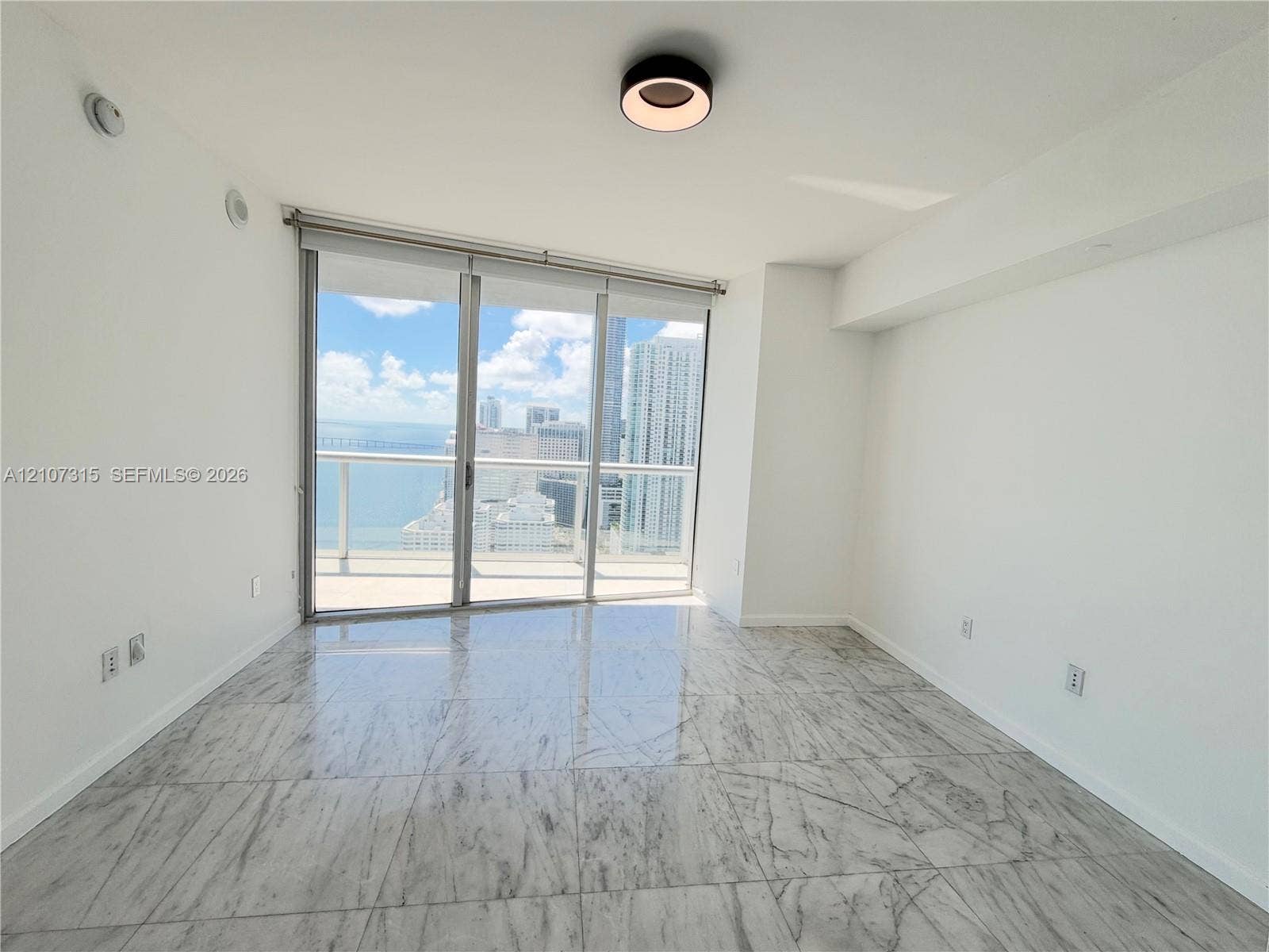 495 Brickell Avenue, #3803, Miami, FL 33131 Floor-to-ceiling sliding glass doors, large-format stone-finish tile flooring, and integrated ceiling lighting