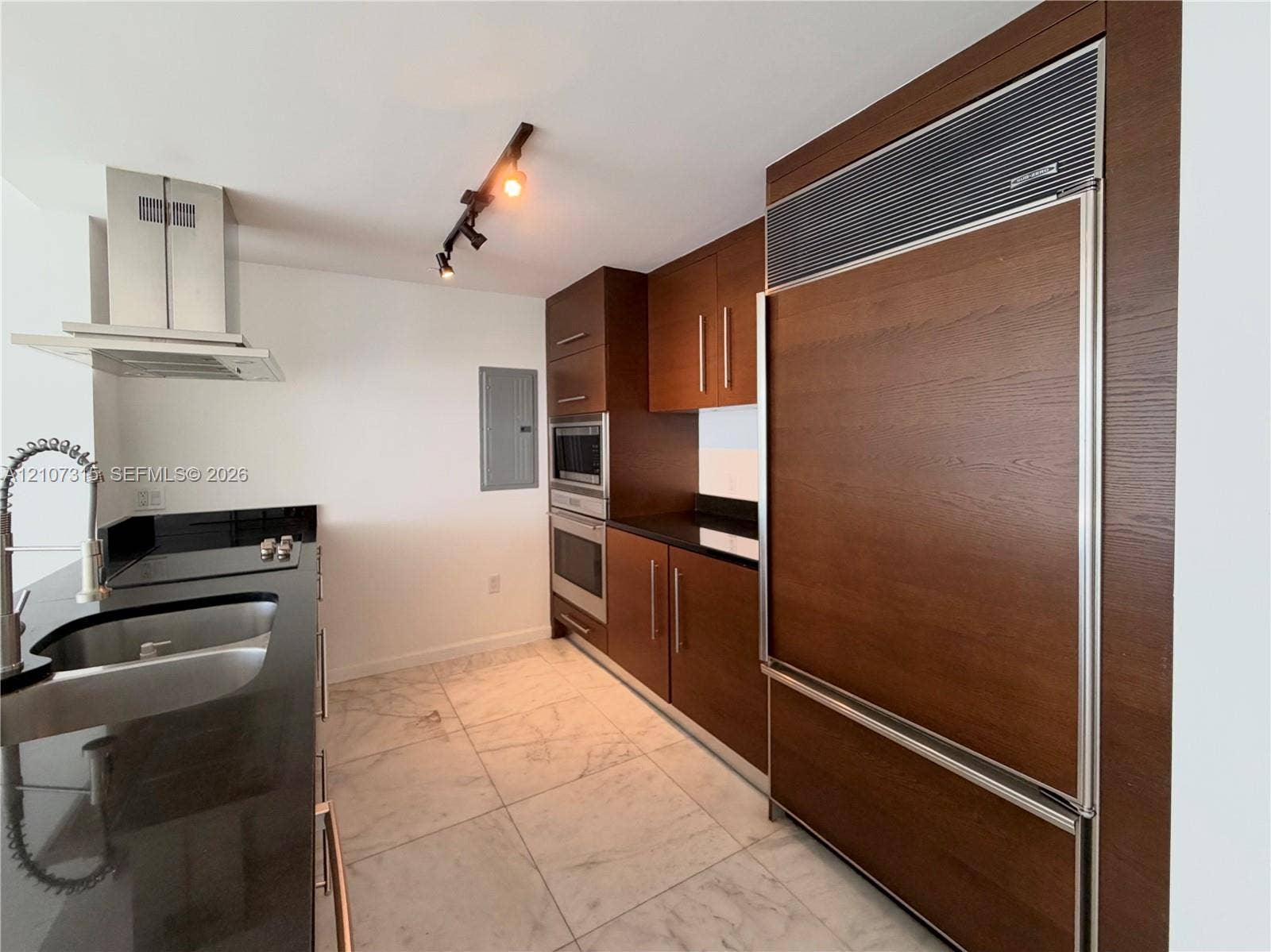 495 Brickell Avenue, #3803, Miami, FL 33131 Kitchen featuring wood-finish cabinetry, integrated panel-ready refrigerator, stainless steel wall-mounted oven and microwave, dark stone-finish countertops, and large-format tile flooring