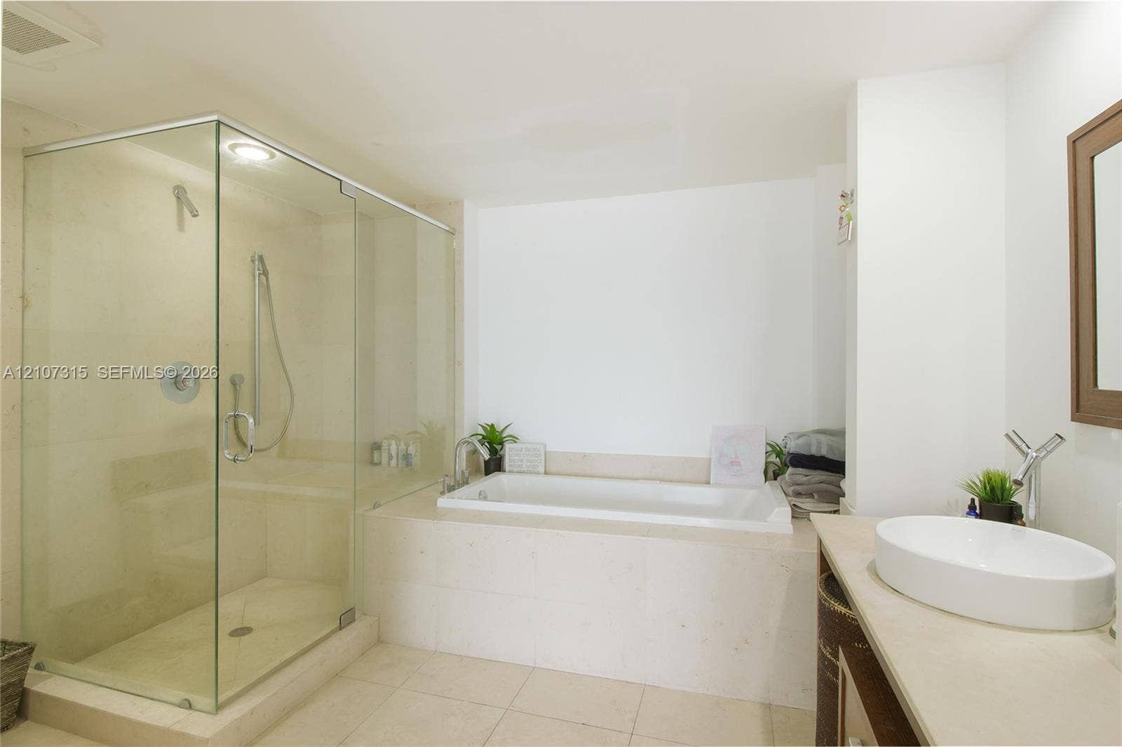 495 Brickell Avenue, #3803, Miami, FL 33131 Glass-enclosed shower with polished metal fixtures, tile-surround bathtub, vanity with stone-finish countertop, and white vessel sink