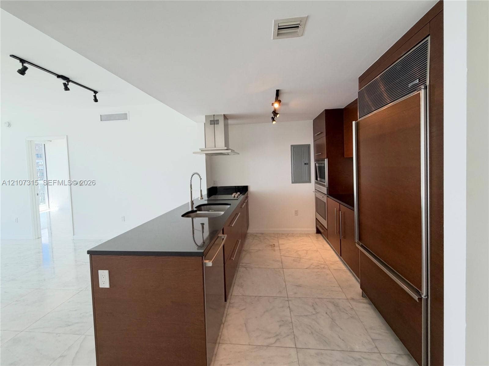 495 Brickell Avenue, #3803, Miami, FL 33131 Kitchen featuring dark wood-finish cabinetry, solid surface countertops, stainless steel appliances, a panel-ready refrigerator, and large-format tile flooring