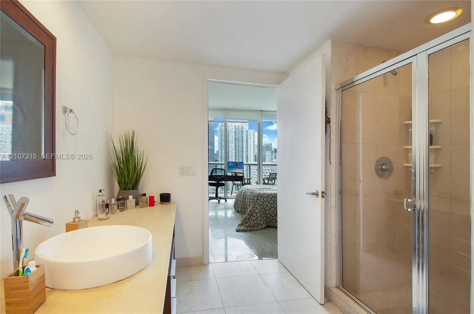 495 Brickell Avenue, #3803, Miami, FL 33131 Bathroom featuring an oval vessel sink, solid surface countertop, chrome single-handle faucet, glass-enclosed shower, and tile flooring