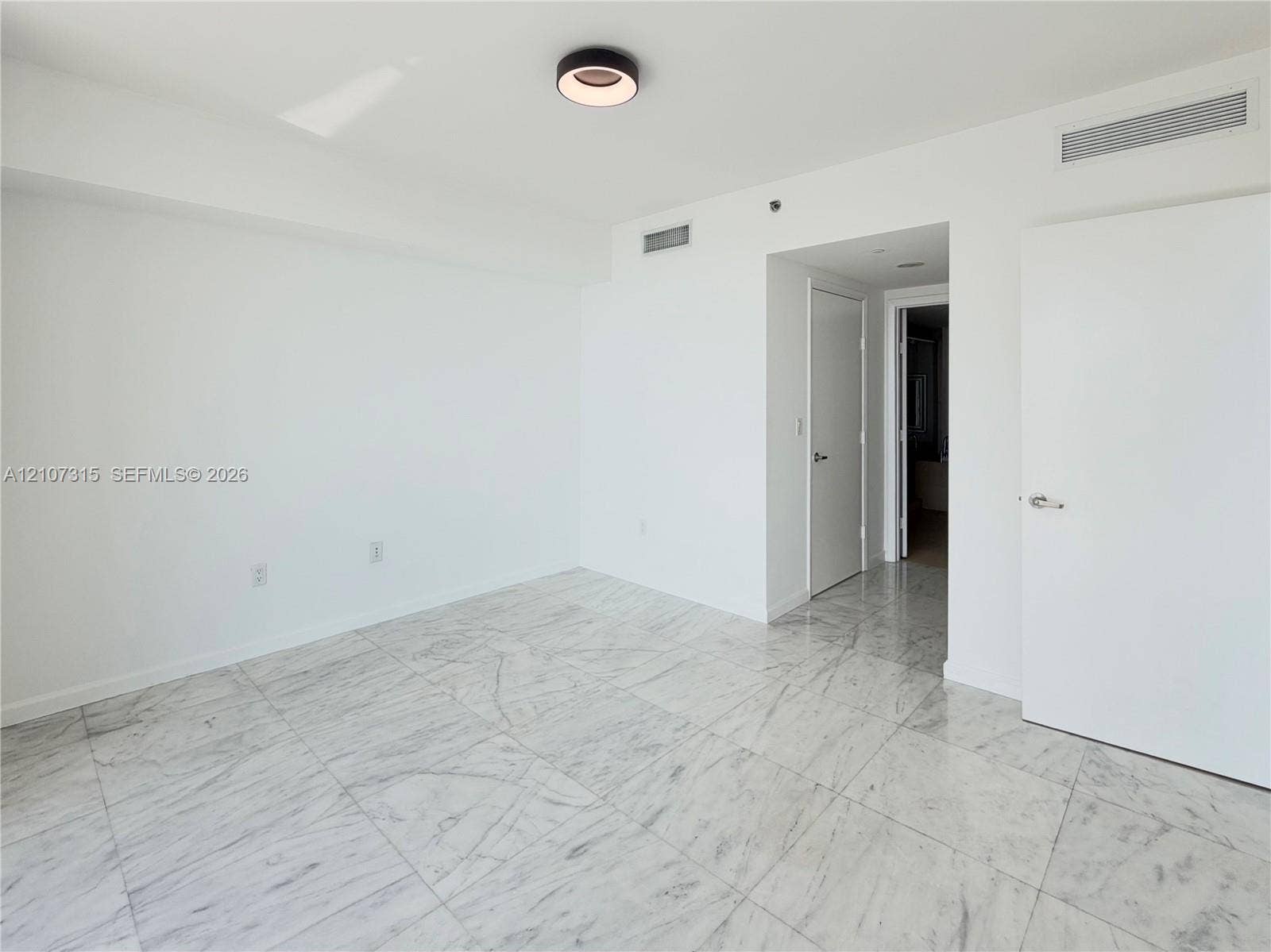495 Brickell Avenue, #3803, Miami, FL 33131 Neutral-toned interior featuring large-format stone-finish tile flooring, solid-core interior doors, and modern circular flush-mount ceiling lighting