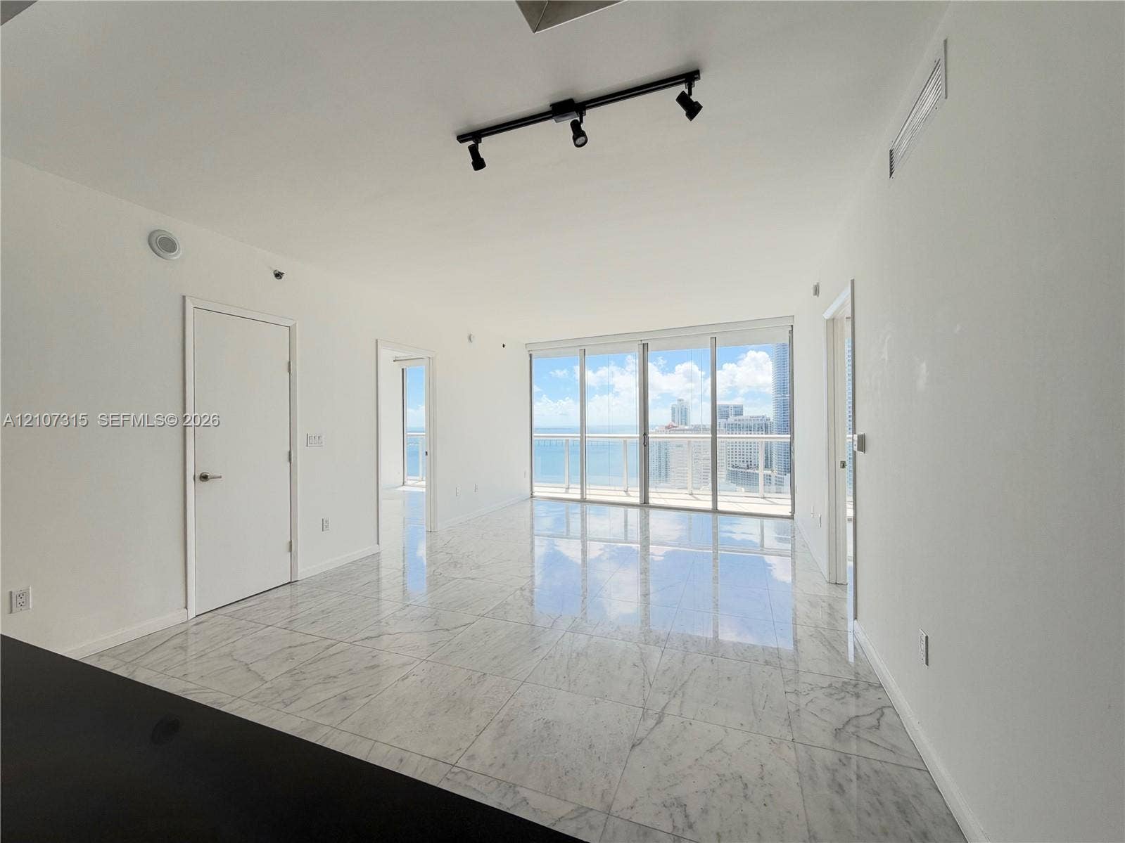 495 Brickell Avenue, #3803, Miami, FL 33131 Open-concept interior featuring floor-to-ceiling glass panel doors, stone-finish tile flooring, and adjustable track lighting