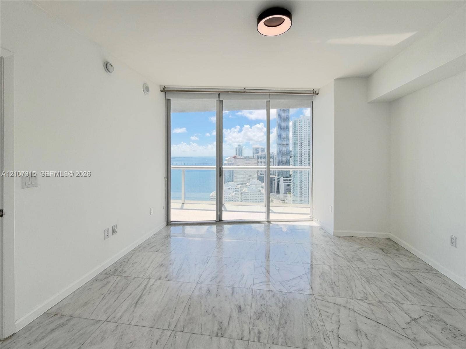 495 Brickell Avenue, #3803, Miami, FL 33131 Polished stone tile flooring, floor-to-ceiling glass sliding doors, private balcony, and urban skyline and water scenery