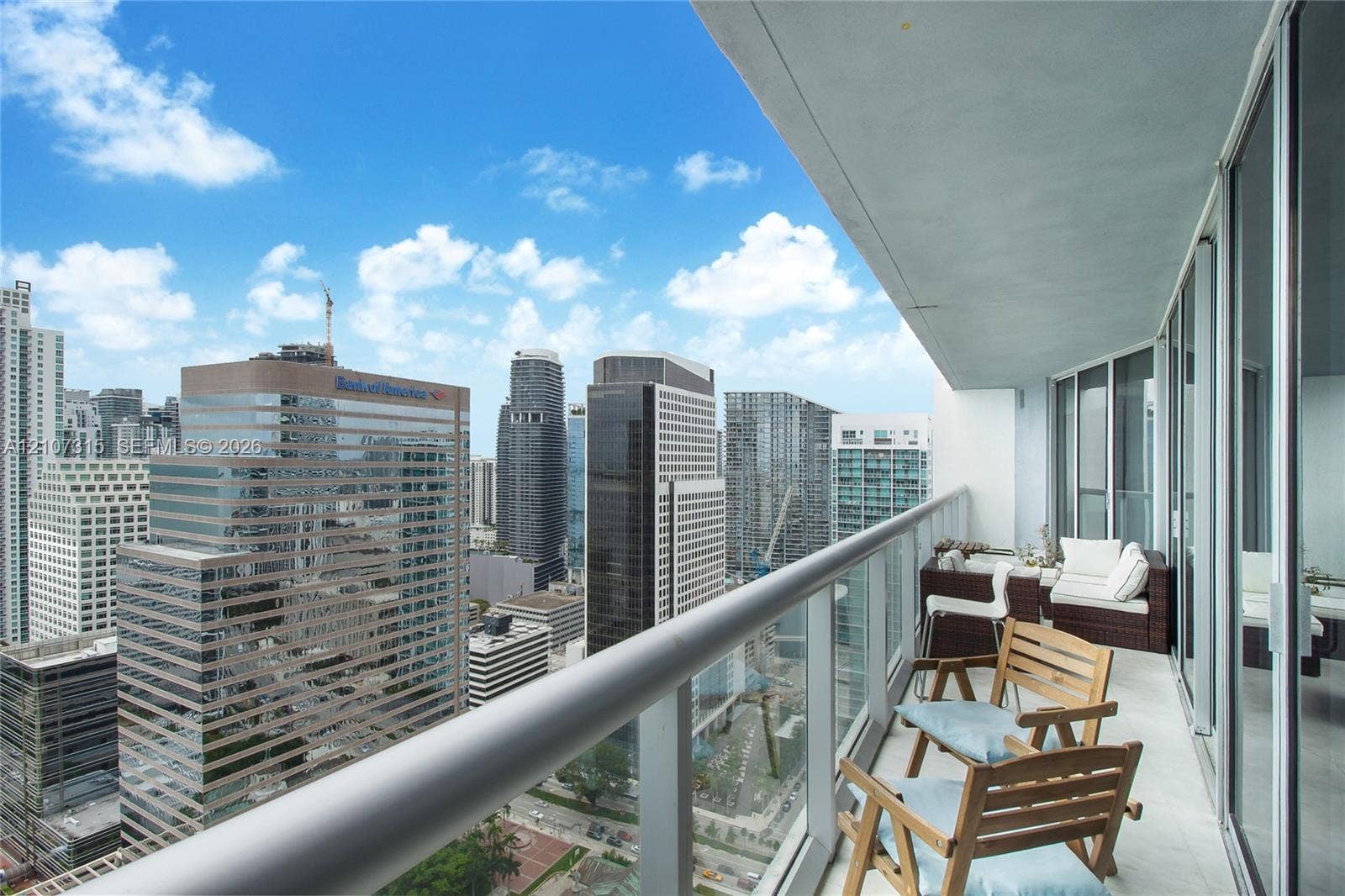 495 Brickell Avenue, #3803, Miami, FL 33131 Covered balcony featuring a glass panel railing, concrete flooring, and metal frame structure, offering an urban skyline panorama