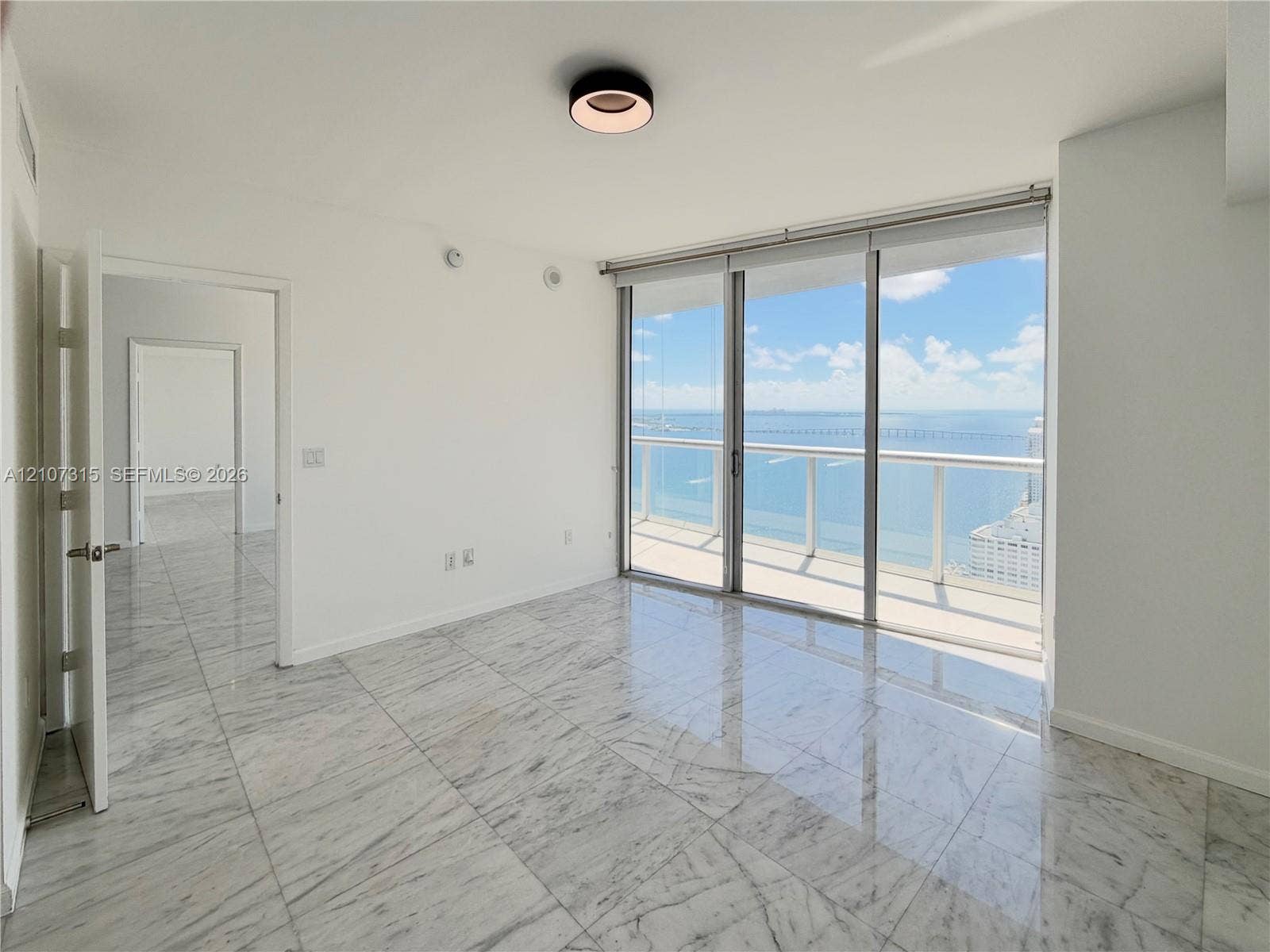 495 Brickell Avenue, #3803, Miami, FL 33131 Polished stone flooring, floor-to-ceiling glass sliding doors, private balcony with metal railing, and circular ceiling-mounted lighting