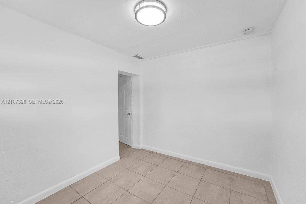 1801 NE 154th Street, #0, North Miami Beach, North Miami Beach, FL 33162 Interior room featuring neutral ceramic tile flooring, crisp white walls, and a circular flush-mount ceiling light fixture