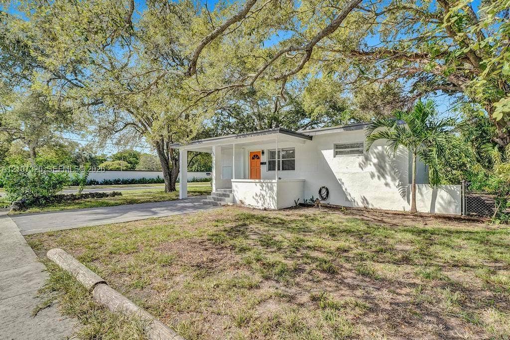 1801 NE 154th Street, #0, North Miami Beach, North Miami Beach, FL 33162 Single-story residence featuring a painted masonry exterior, covered front porch, concrete driveway, and mature landscaping