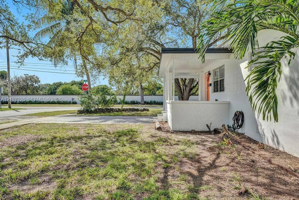 1801 NE 154th Street, #0, North Miami Beach, North Miami Beach, FL 33162 Exterior facade with white masonry construction, covered front porch, and mature shade trees