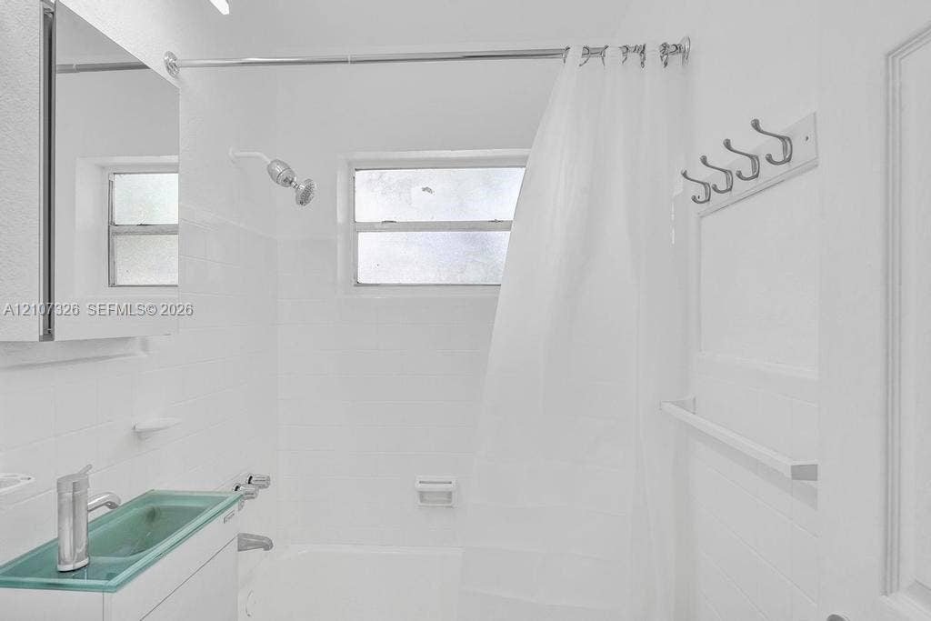 1801 NE 154th Street, #0, North Miami Beach, North Miami Beach, FL 33162 Bathroom featuring a glass vessel sink, chrome fixtures, a combination tub and shower with tile surround, and a wall-mounted hook rack