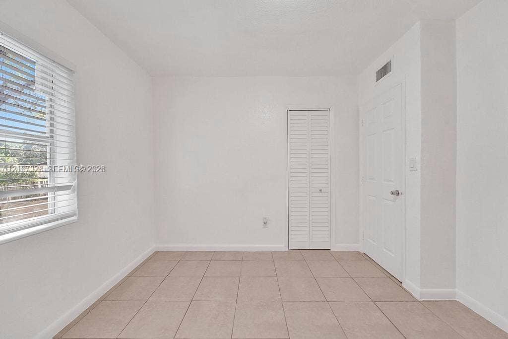1801 NE 154th Street, #0, North Miami Beach, North Miami Beach, FL 33162 Neutral-toned tile flooring, white interior walls, white paneled door, louvered-style closet door, and window with horizontal blinds