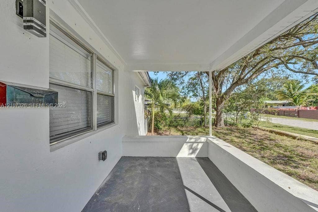 1801 NE 154th Street, #0, North Miami Beach, North Miami Beach, FL 33162 Covered porch featuring concrete flooring, a smooth white ceiling, exterior wall-mounted lighting, and a metal mailbox