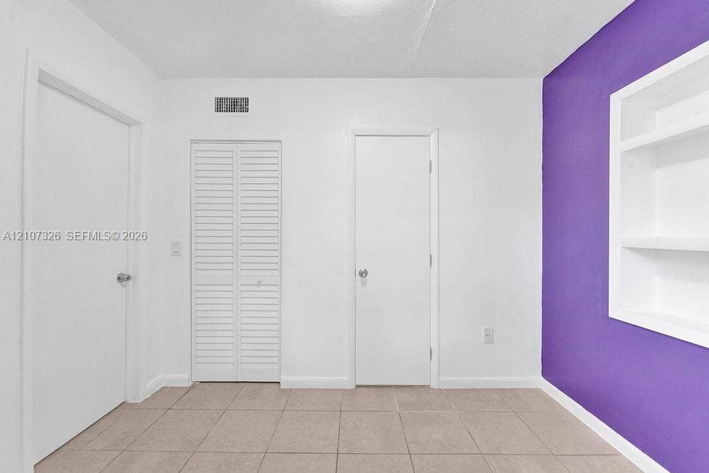 1801 NE 154th Street, #0, North Miami Beach, North Miami Beach, FL 33162 Neutral-toned tile flooring, built-in shelving unit, and louvered closet doors